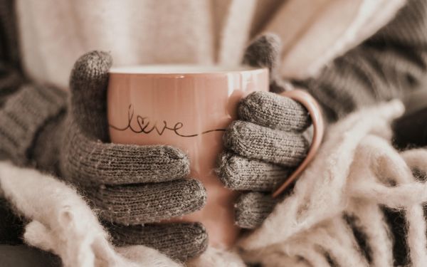 Eine Frau hält eine wärmende Tasse in beiden Händen